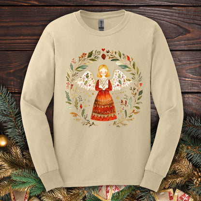 Sand Gildan long sleeve tee with a folk art angel in a winter wreath of red, green, and gold.