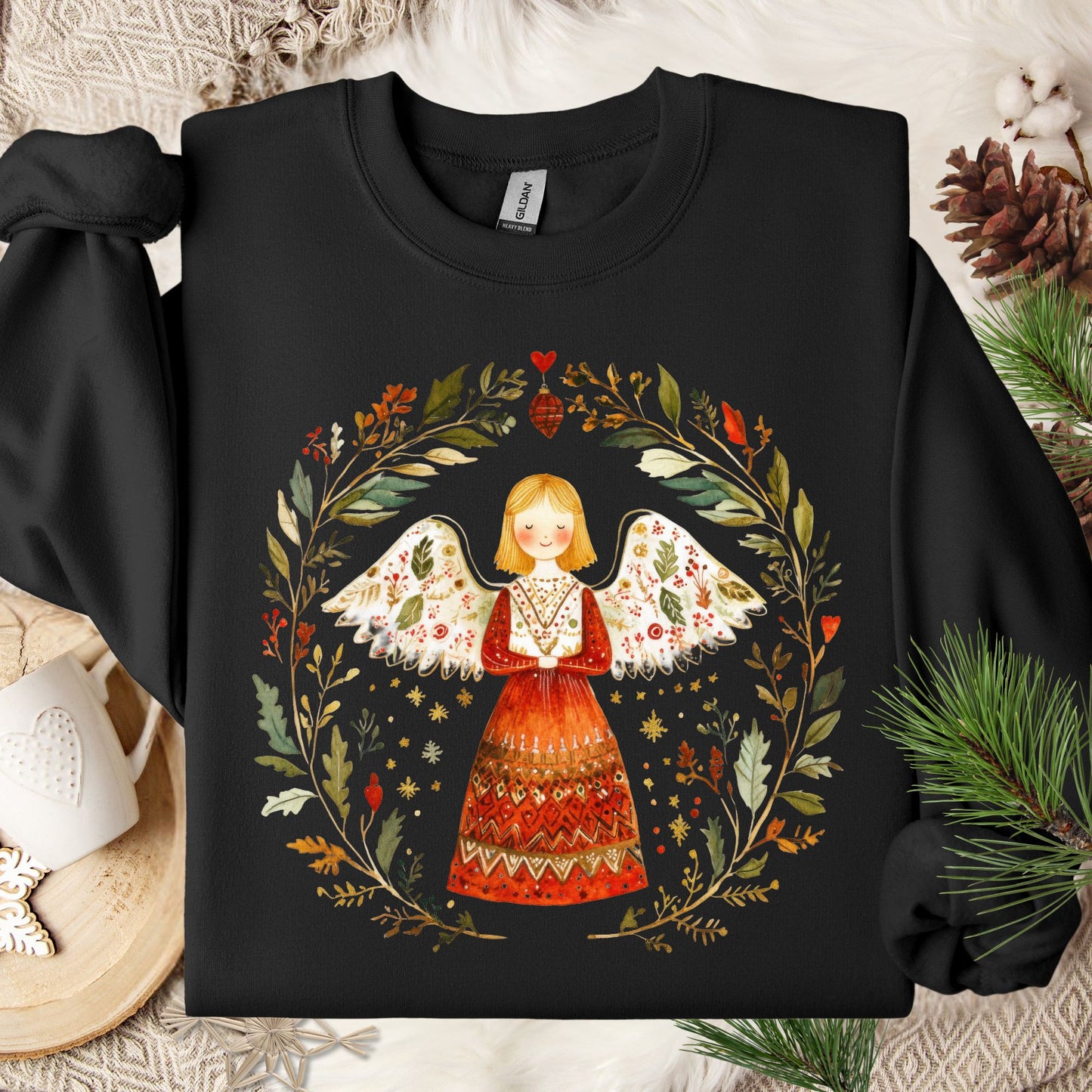 Black S sweatshirt with a folk art angel in a winter wreath, featuring red, green, and golden hues.