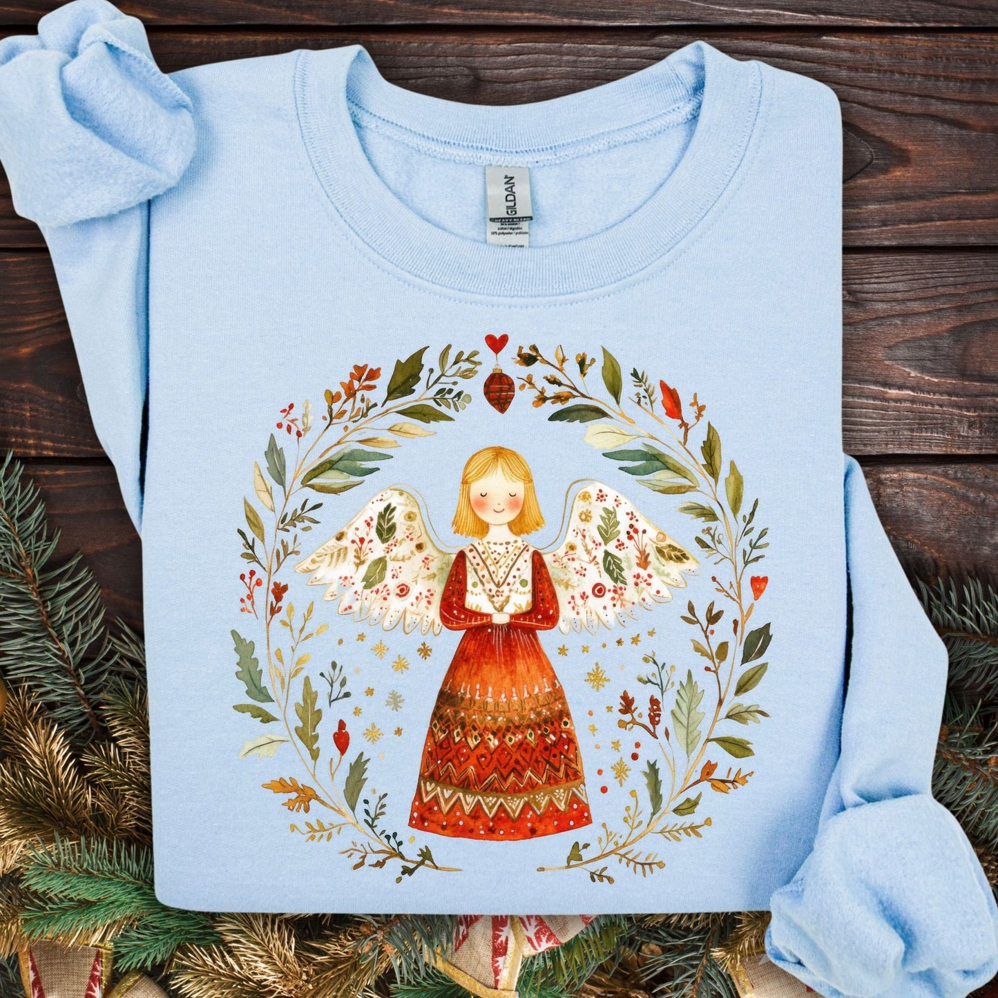 Light blue fleece sweatshirt with a folk art angel in a winter wreath design.
