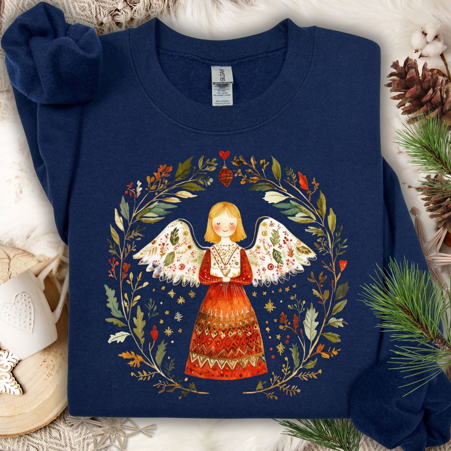 Navy S sweatshirt with a folk art winter angel in a wreath of red, green, and golden foliage.