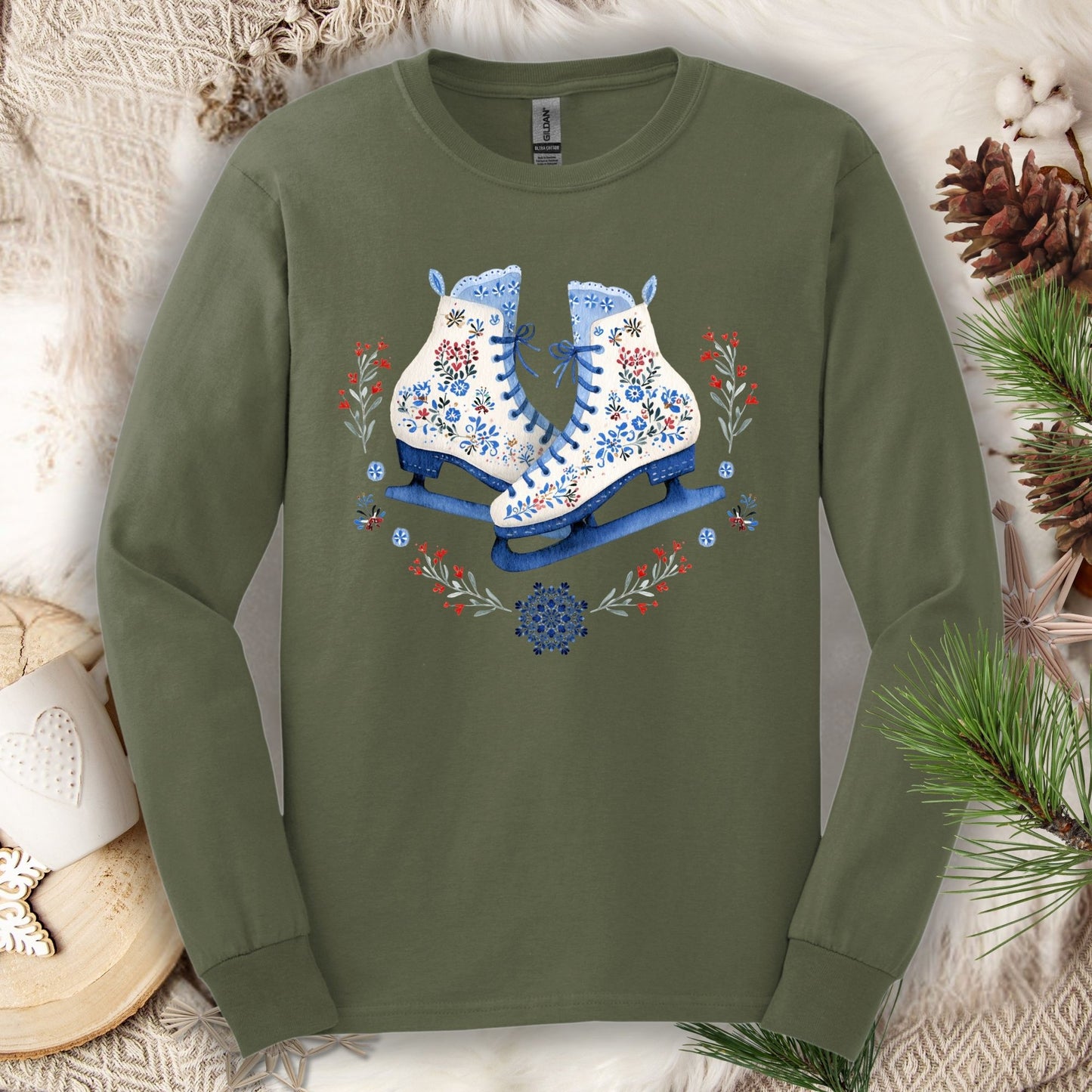 Military Green long sleeve tee with folk art winter ice skates in blues, reds, and whites, surrounded by florals.