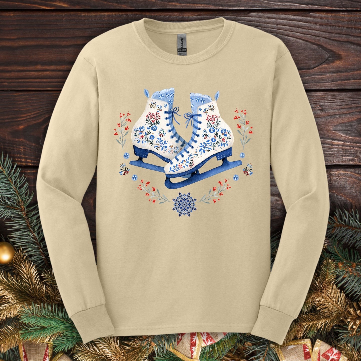 Sand long sleeve tee with folk art winter ice skates in blue, red, and white floral designs.