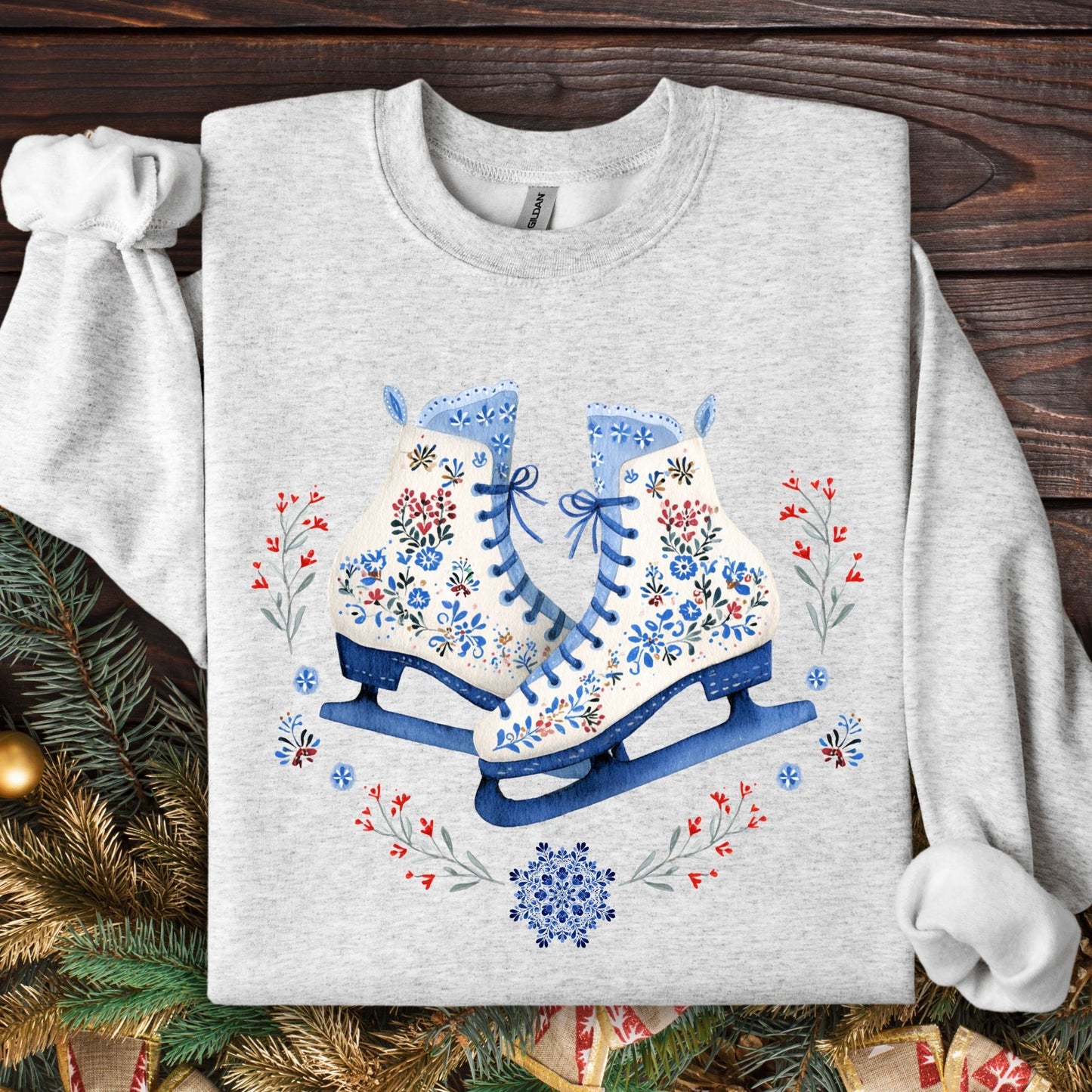 Ash S sweatshirt with folk art ice skates, blue, white, red floral embroidery, and winter greenery.