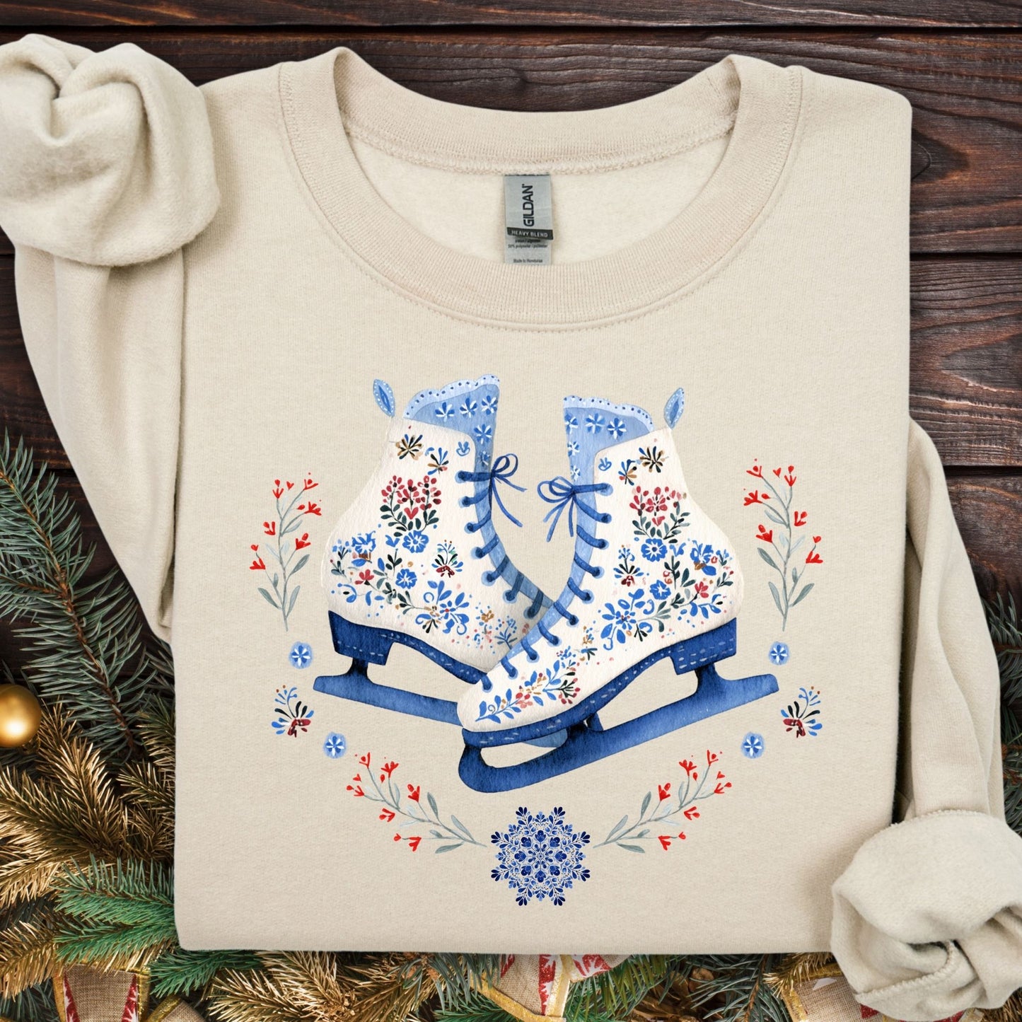 Sand heavyweight fleece sweatshirt with folk art ice skates in blue, white, and red, surrounded by winter greenery.