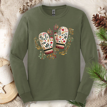Military green long sleeve tee with watercolor folk art mittens in red, cream, evergreen, and gold, surrounded by winter foliage.