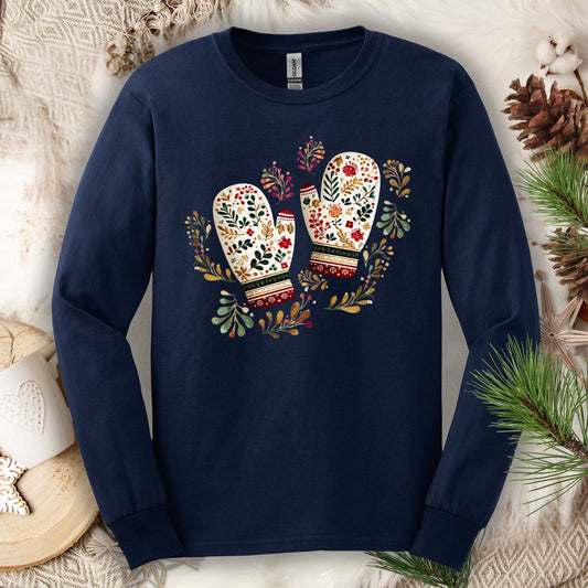 Navy long sleeve tee with watercolor folk art mittens in red, cream, evergreen, and gold, surrounded by winter foliage.
