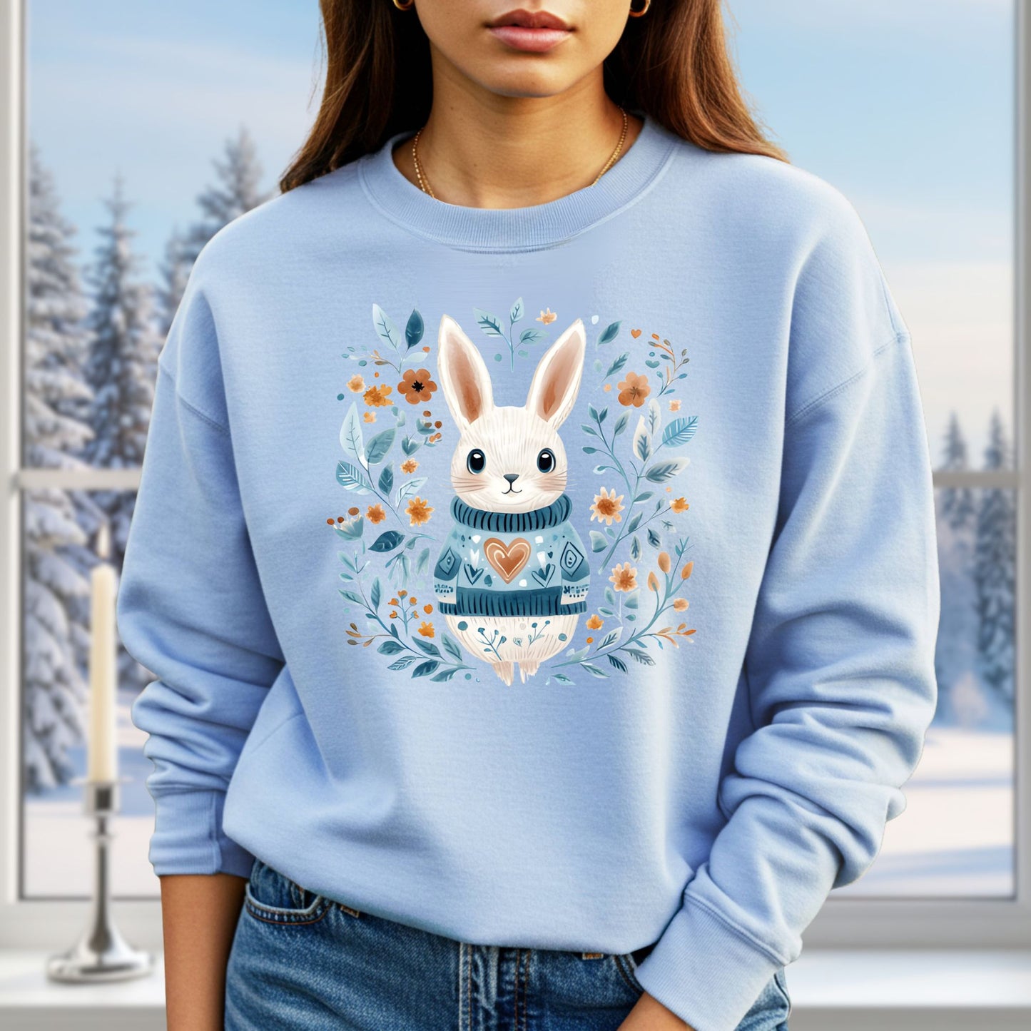 Light blue sweatshirt with a folk art winter rabbit wearing a heart sweater, surrounded by floral designs.