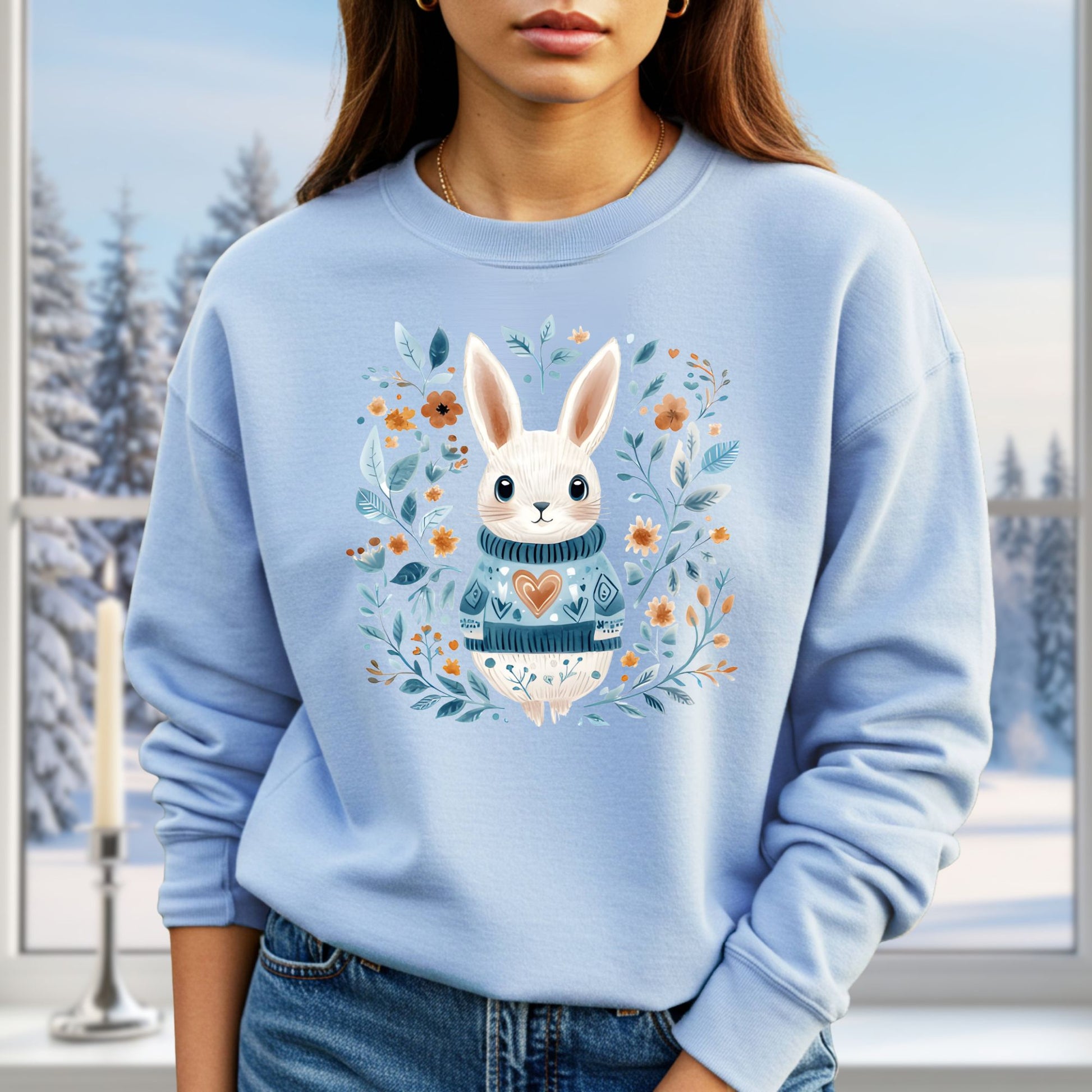 Light blue sweatshirt with a folk art winter rabbit wearing a heart sweater, surrounded by floral designs.