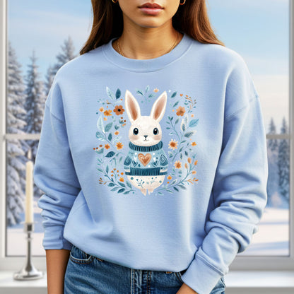 Light blue sweatshirt with a folk art winter rabbit wearing a heart sweater, surrounded by floral designs.