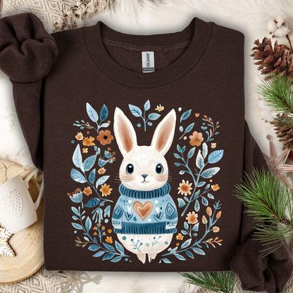Dark chocolate sweatshirt with a folk art winter rabbit wearing a blue sweater, surrounded by floral designs.