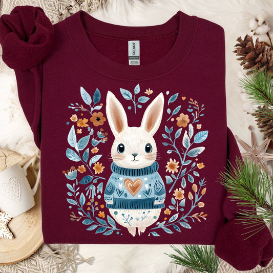 Maroon Folk Art Winter Rabbit sweatshirt with a whimsical bunny in a blue sweater, surrounded by floral designs.