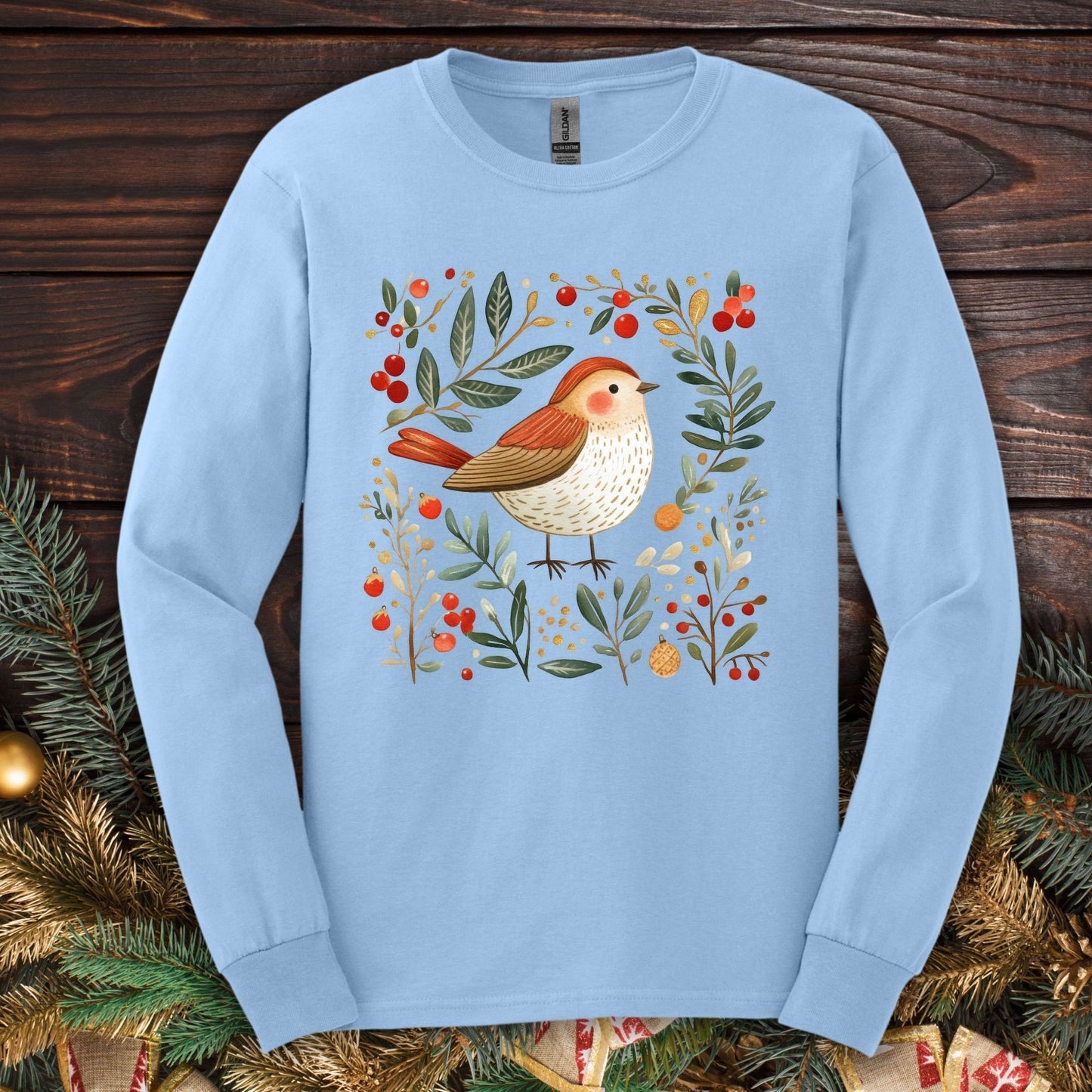Light blue Gildan Softstyle long sleeve tee with folk art winter sparrow, evergreens, holly, and ornaments.