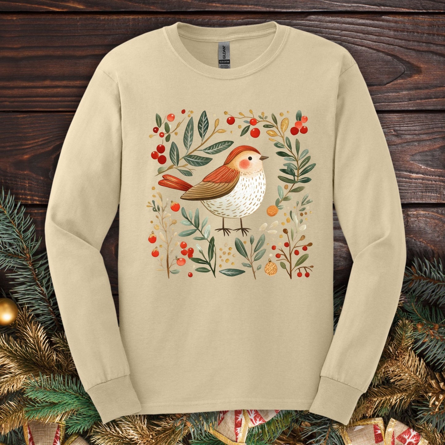 Sand Gildan Softstyle long sleeve tee with folk art winter sparrow, evergreens, holly, and ornaments.