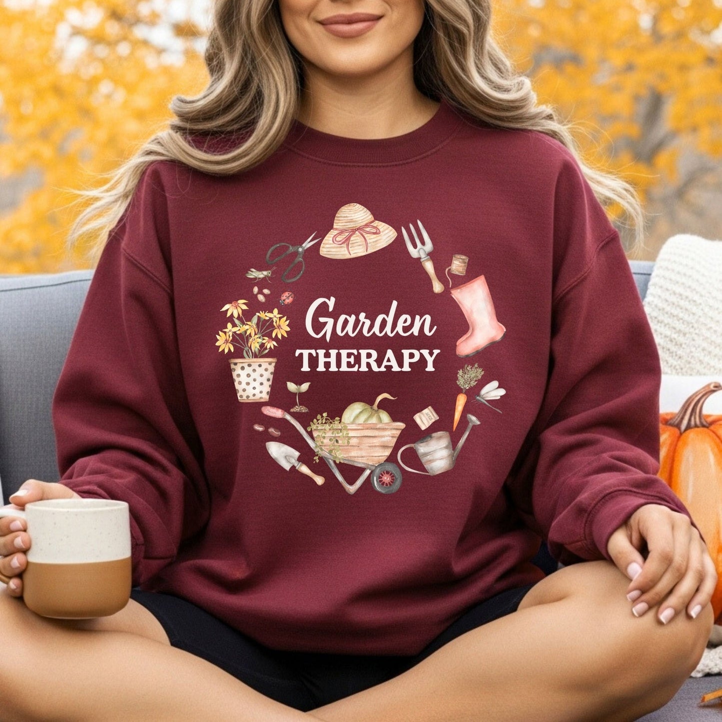 Maroon crewneck sweatshirt with "Garden Therapy" and a wreath of gardening tools, boots, and blooms.