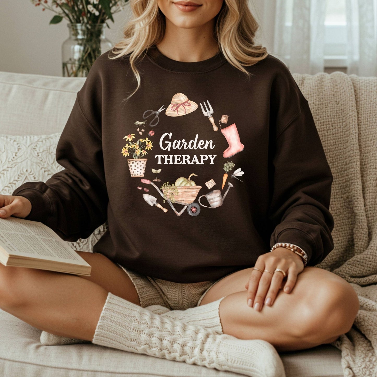 Woman in a dark brown crewneck sweatshirt with a colorful "Garden Therapy" floral wreath design.