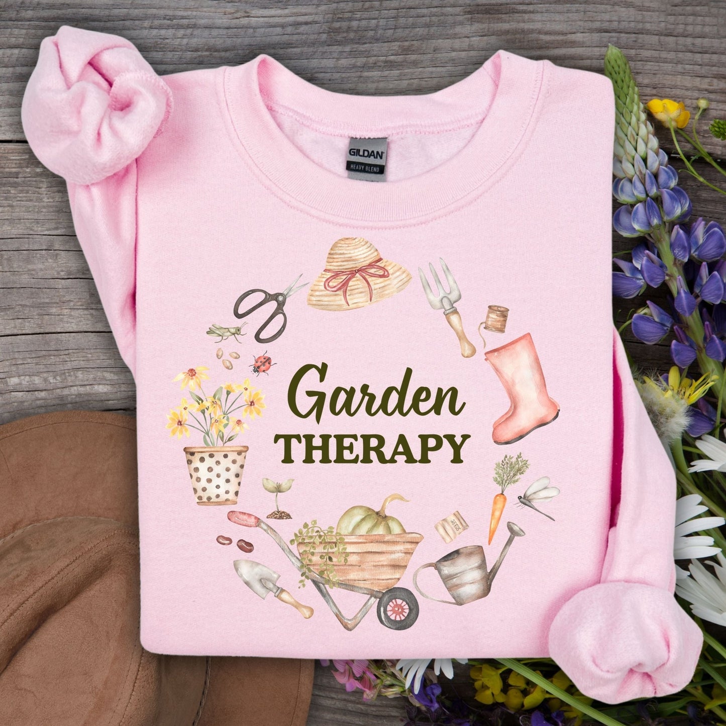 Light pink Garden Therapy sweatshirt with a floral wreath of gardening tools and blooms.