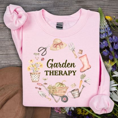Light pink Garden Therapy sweatshirt with a floral wreath of gardening tools and blooms.