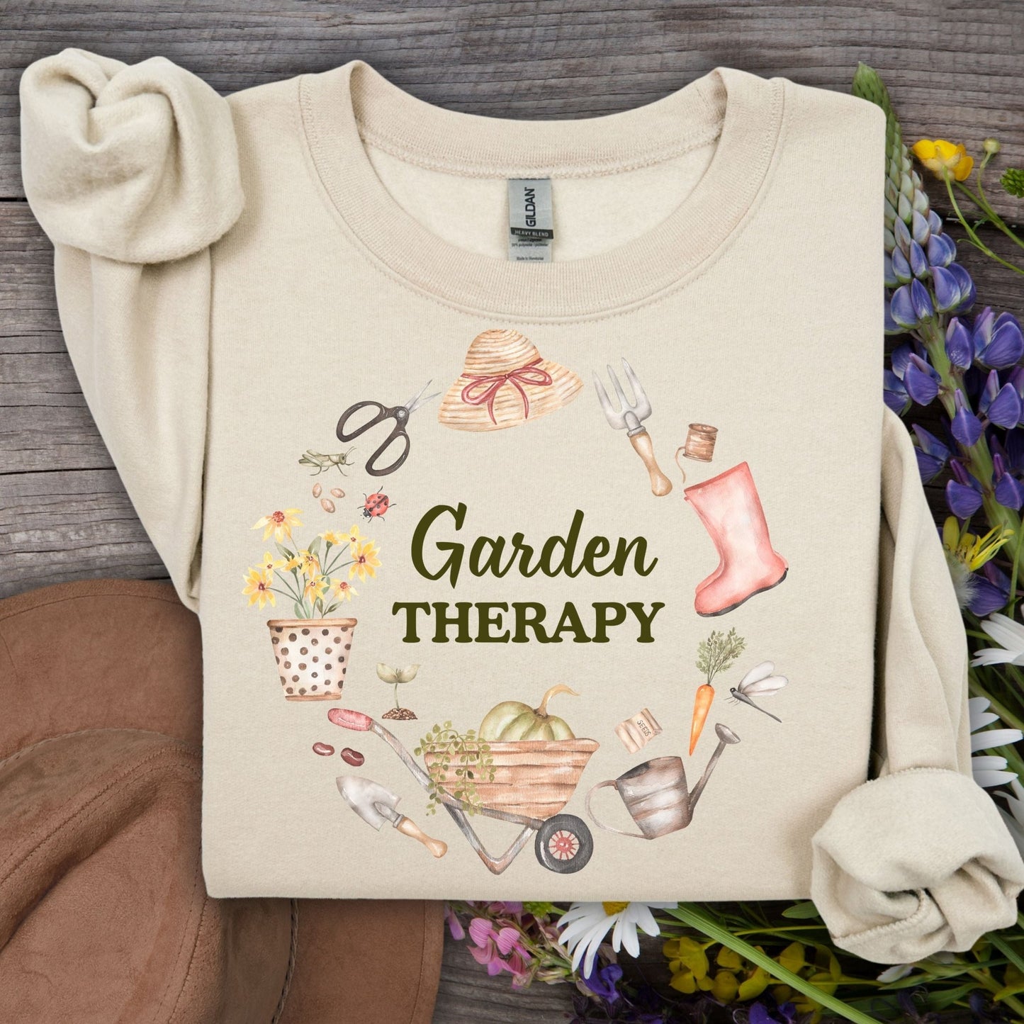 Sand crewneck sweatshirt with "Garden Therapy" text surrounded by a wreath of watercolor gardening tools and flowers.