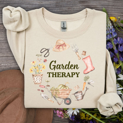Sand crewneck sweatshirt with "Garden Therapy" text surrounded by a wreath of watercolor gardening tools and flowers.