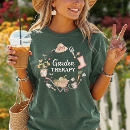 Woman in a relaxed-fit, dark green "Garden Therapy" t-shirt with a floral wreath design, holding iced coffee.