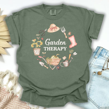 Moss green garment-dyed t-shirt with "Garden Therapy" in a floral wreath design, paired with jeans.