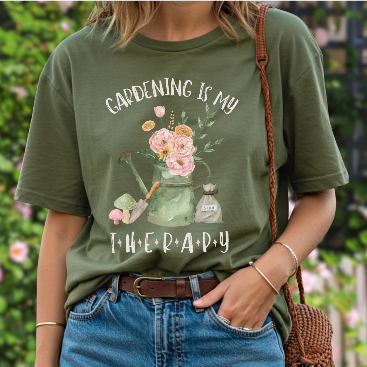Olive green cotton t-shirt with "Gardening Is My Therapy" and a watercolor watering can, flowers, trowel, mushrooms, and seed bag.