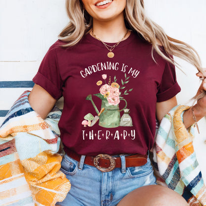 Woman wearing a maroon t-shirt with 'Gardening is my Therapy' design, sitting on a colorful blanket.