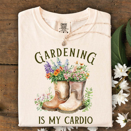 Beige t-shirt with gardening graphic and text on a wooden background that reads "Gardening is my cardio"