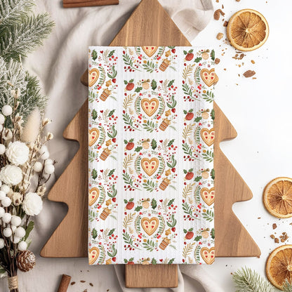 White 16x25" microfiber tea towel with a folk art gingerbread heart, holly, and evergreen pattern.