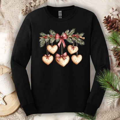 Black long-sleeve tee with a watercolor gingerbread heart garland design, ribbed cuffs, and double-stitched hems.