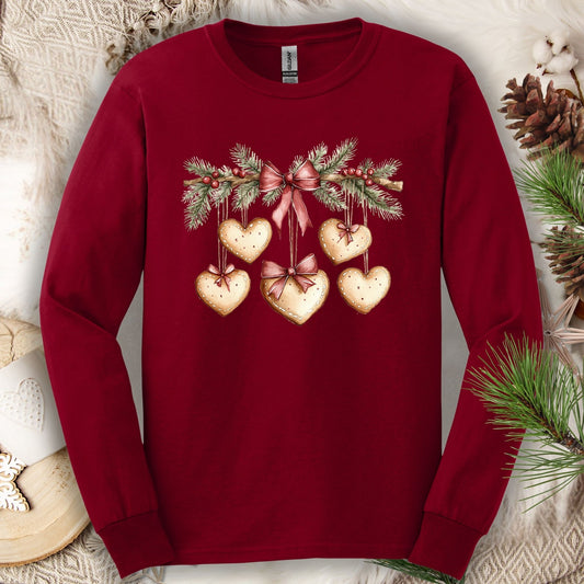 Cardinal Red long sleeve tee with watercolor gingerbread heart garland design, ribbed cuffs, and double-stitched hems.