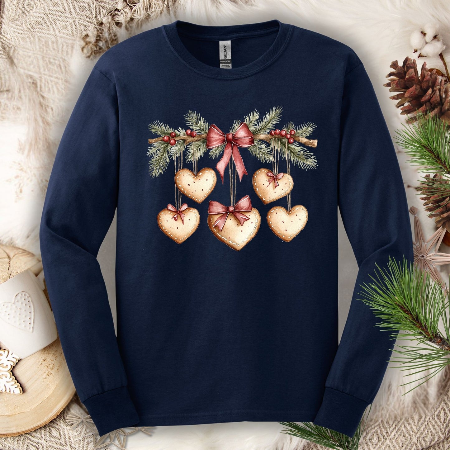 Navy long sleeve tee with a watercolor gingerbread heart garland design, ribbed cuffs, and double-stitched hems.