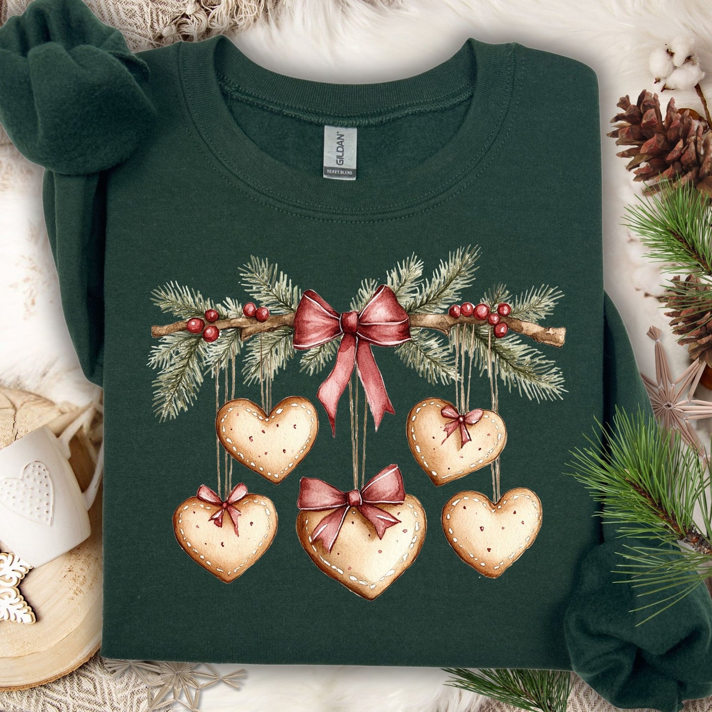 Forest green sweatshirt with watercolor evergreen garland, red bow, and heart-shaped gingerbread cookies.