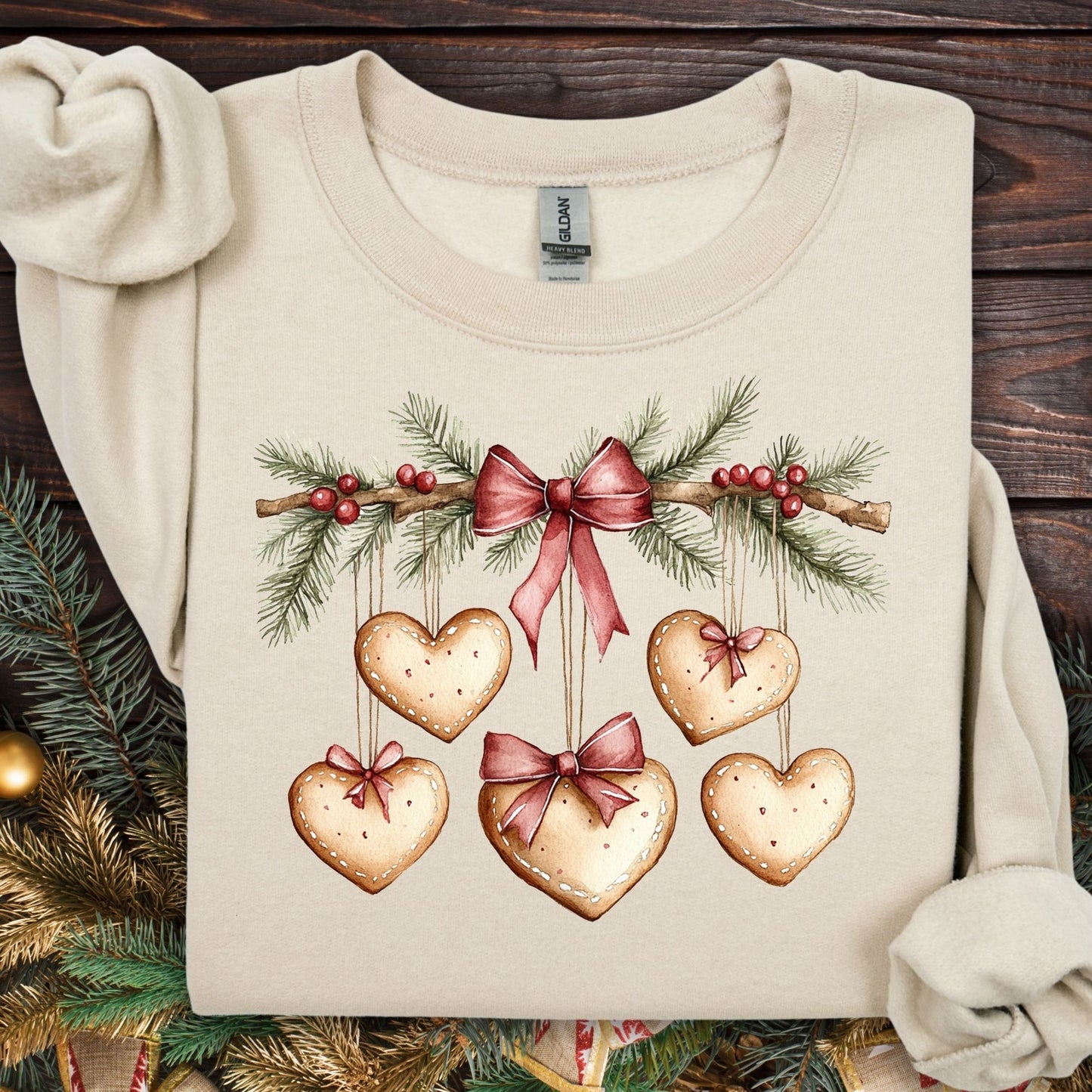 Sand S sweatshirt with watercolor evergreen garland, red bow, and hanging heart gingerbread cookies.
