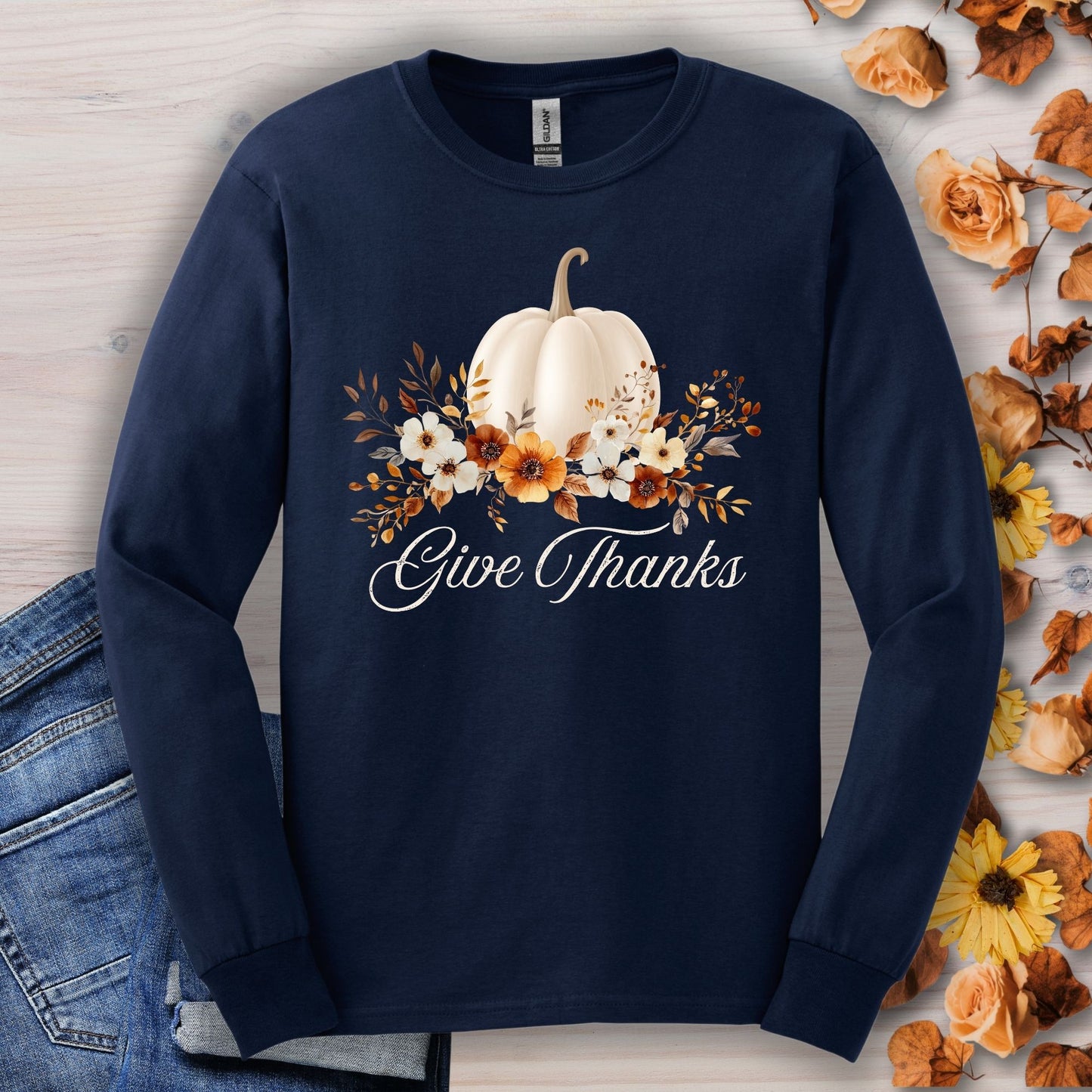 Navy long sleeve tee with a white watercolor pumpkin, autumn foliage, and "Give Thanks" text.