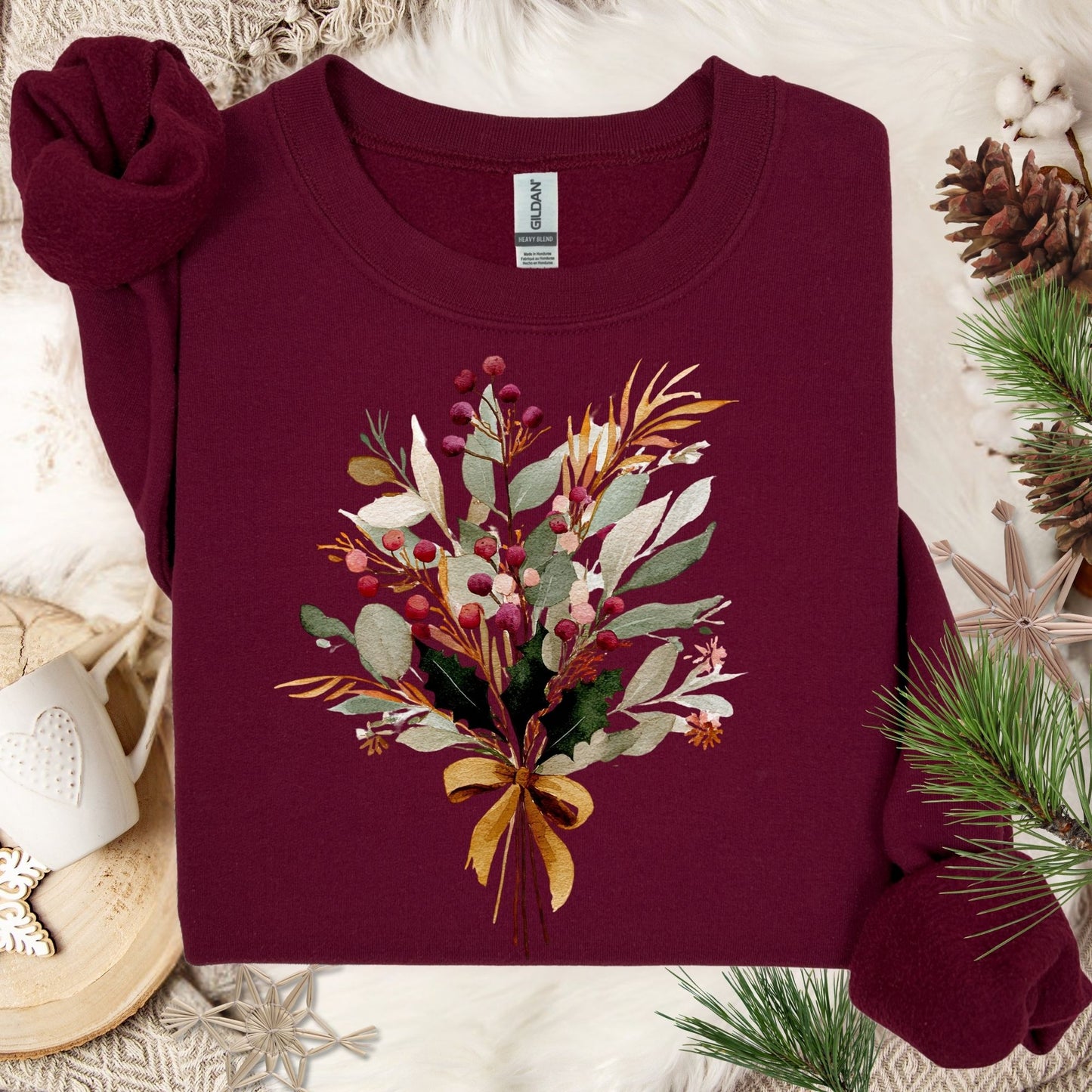 Maroon Gildan sweatshirt with a watercolor Christmas bouquet tied with a golden bow, featuring berries, eucalyptus, and evergreens.