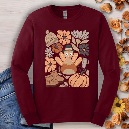 Maroon long sleeve tee with a "Groovy Turkey" graphic surrounded by fall essentials like boots, pumpkins, and flowers.