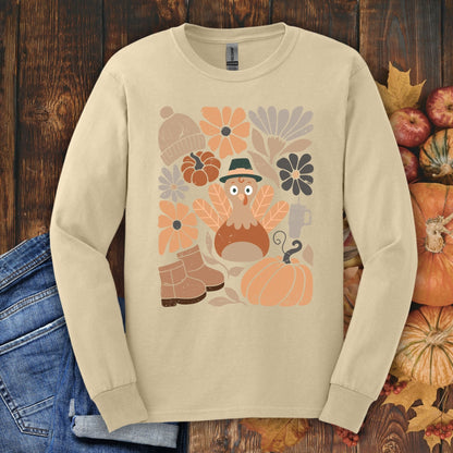 Sand Gildan 2400 long sleeve tee with a "Groovy Turkey" graphic, surrounded by fall boots, leaves, and pumpkins.