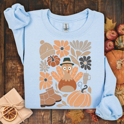 Light blue Gildan sweatshirt with a groovy turkey, fall leaves, boots, hat, and rustic florals.