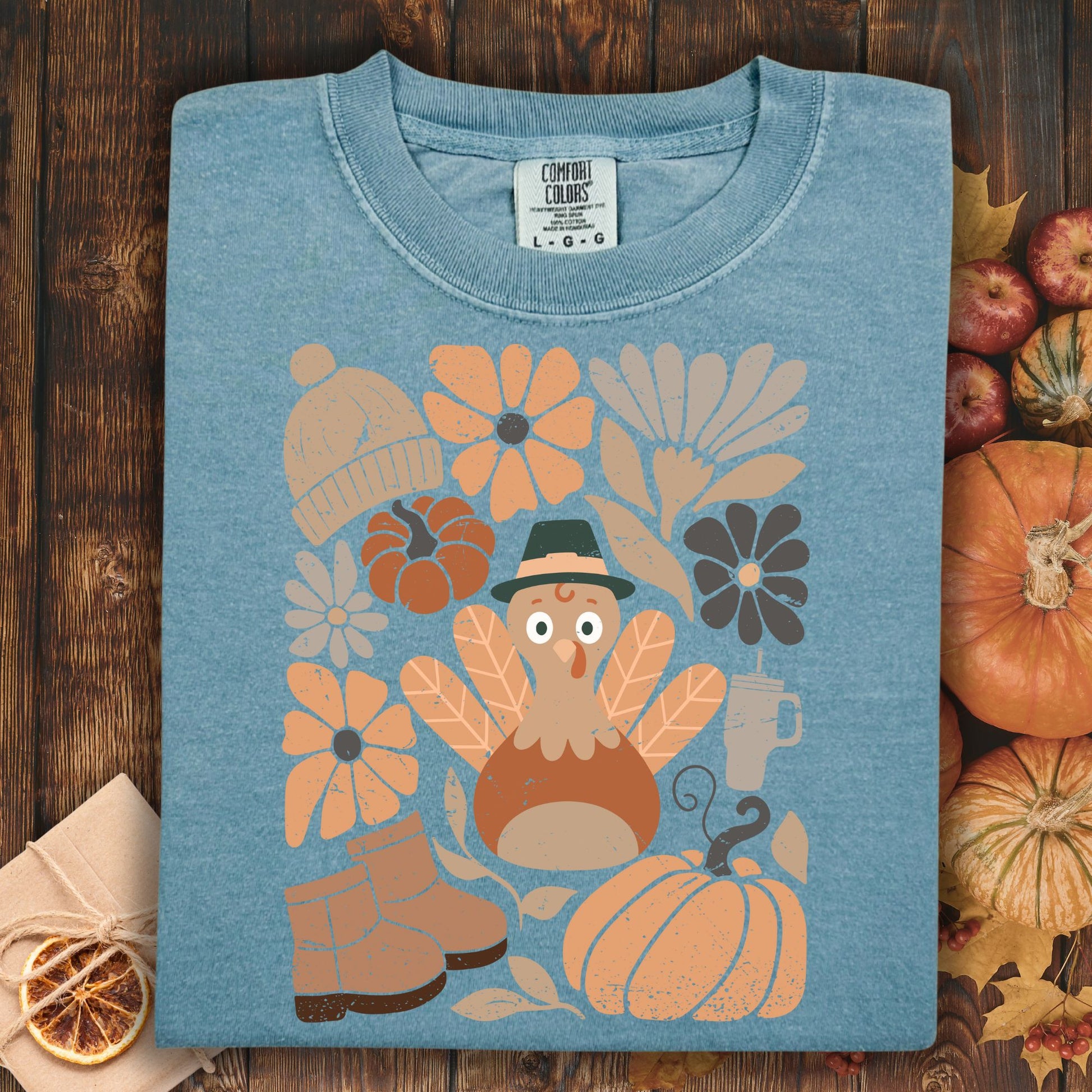 Ice Blue Comfort Colors t-shirt with a groovy turkey, pumpkins, boots, and autumn flowers design.