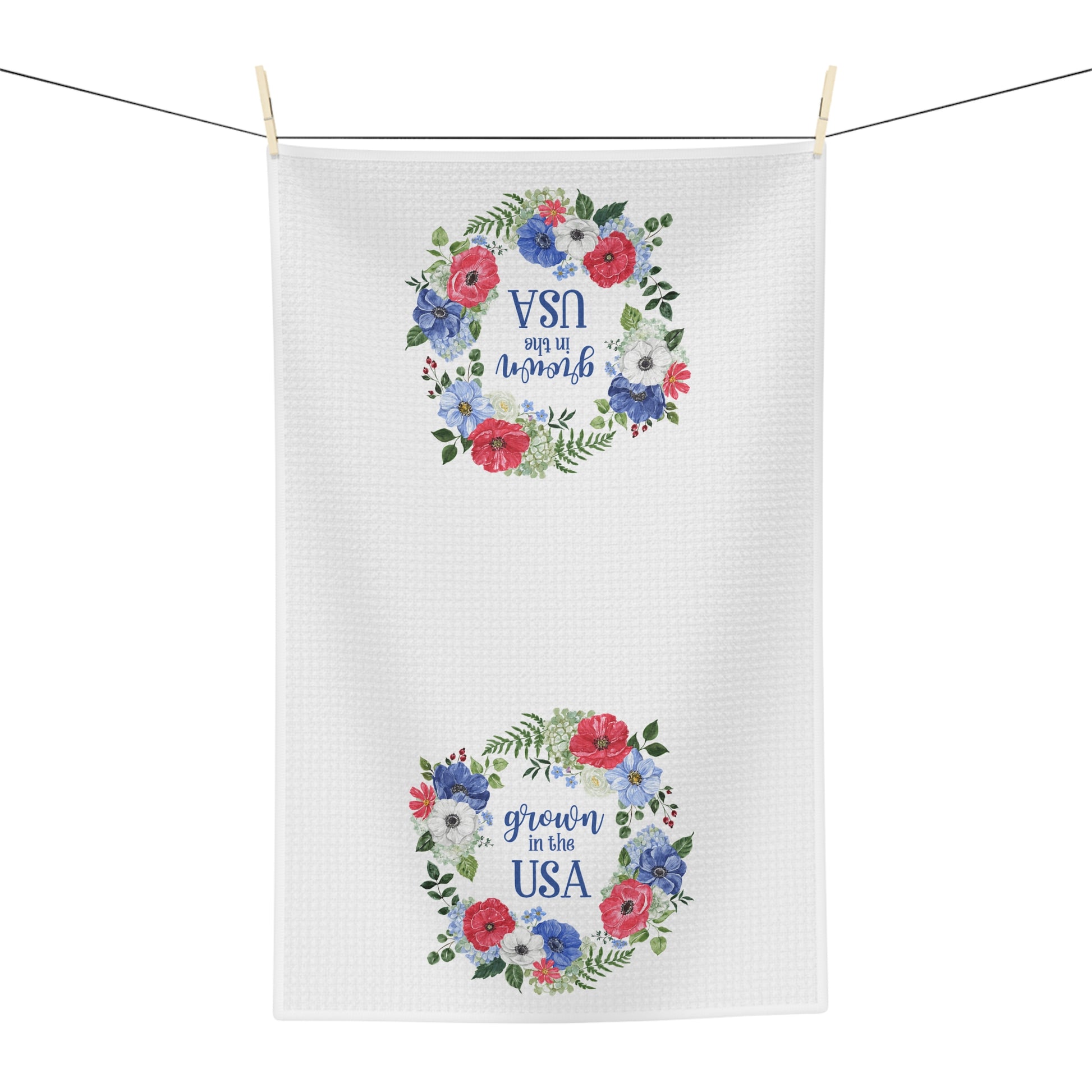 White microfiber tea towel with two red, blue, and green floral wreaths framing "grown in the USA.