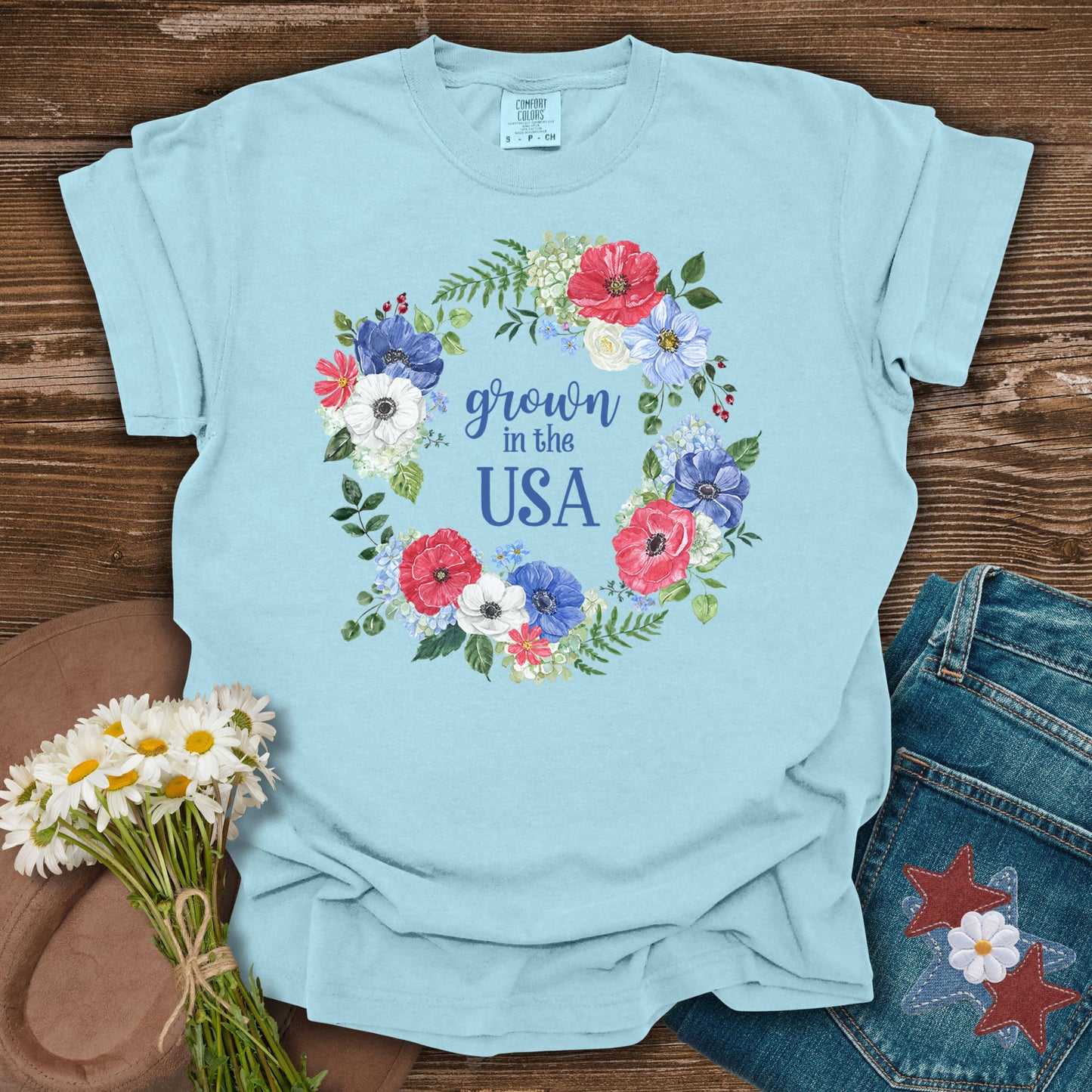 Chambray blue t-shirt with a watercolor floral wreath design and "Grown in the USA" text.