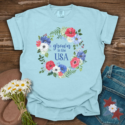 Chambray blue t-shirt with a watercolor floral wreath design and "Grown in the USA" text.