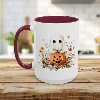 White ceramic mug with a watercolor ghost holding a jack-o'-lantern, surrounded by wildflowers. Maroon handle and interior.