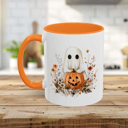 White ceramic mug with orange handle and interior, featuring a watercolor ghost holding a jack-o'-lantern amidst wildflowers.