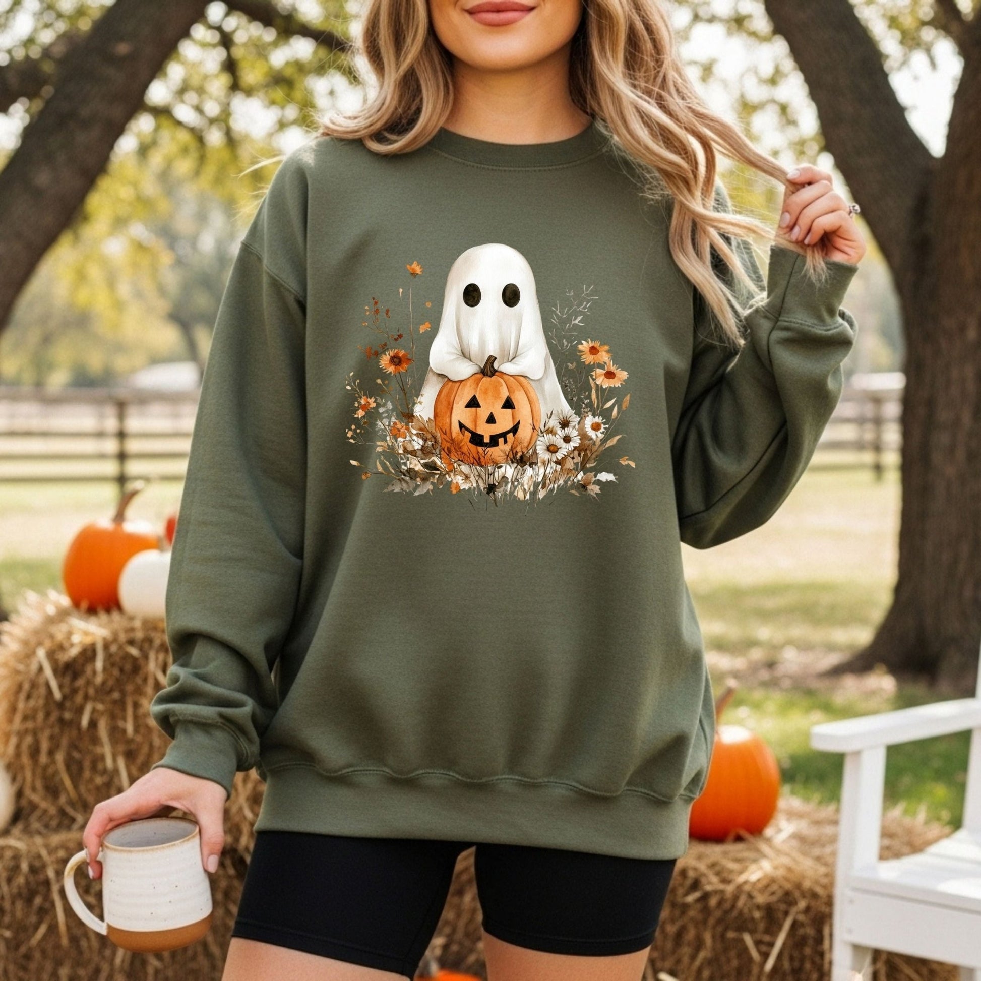 Boho ghost holding a jack o'lantern, surrounded by autumn wildflowers on a dark green sweatshirt.