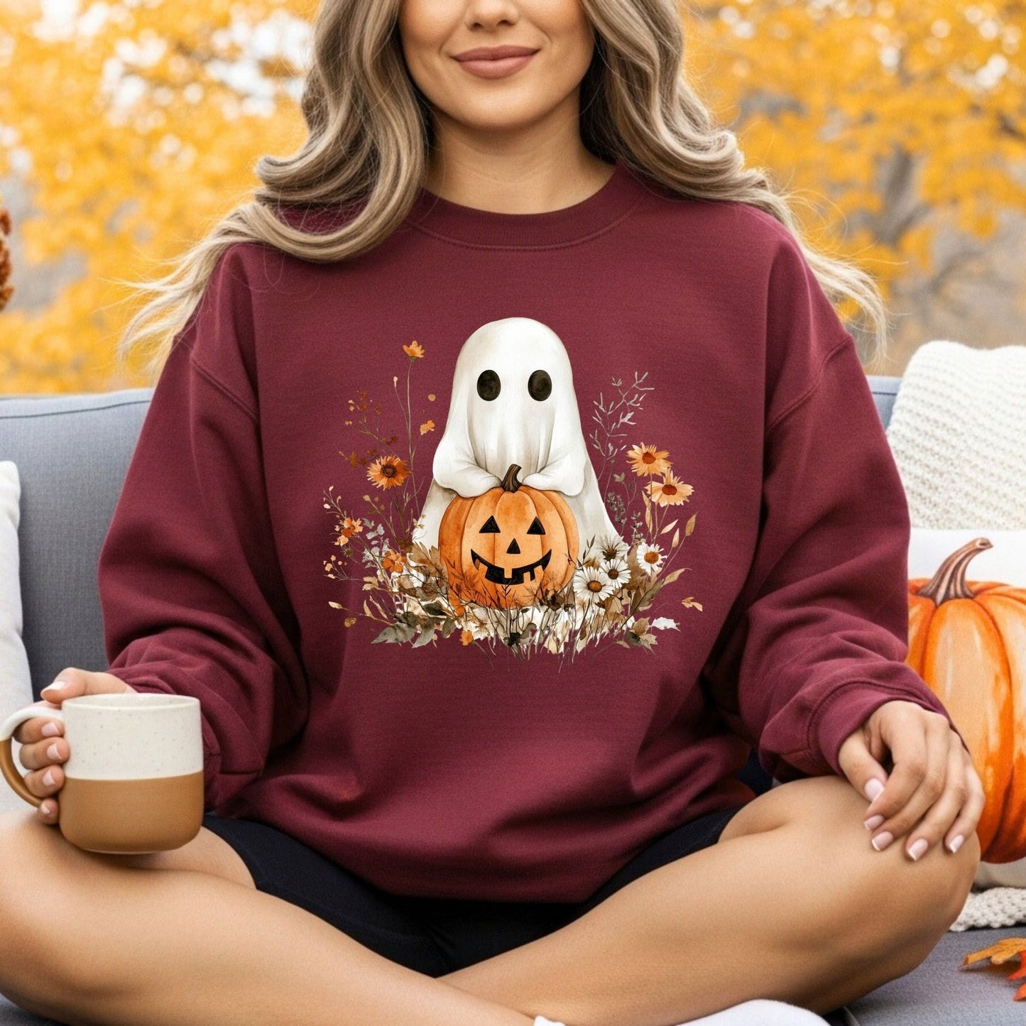Maroon unisex sweatshirt with a cute boho ghost holding a jack o'lantern, surrounded by autumn wildflowers.
