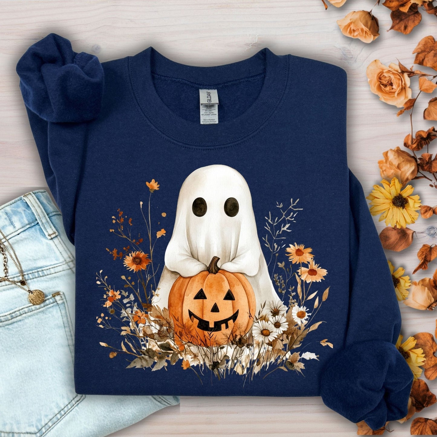 Navy Halloween sweatshirt with a boho ghost holding a jack o'lantern, surrounded by autumn wildflowers.
