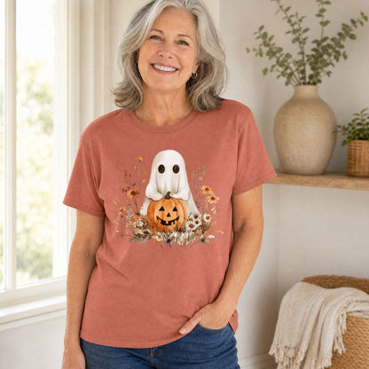 Woman in a relaxed-fit, rust-colored cotton t-shirt with a boho ghost holding a jack o'lantern and autumn florals.