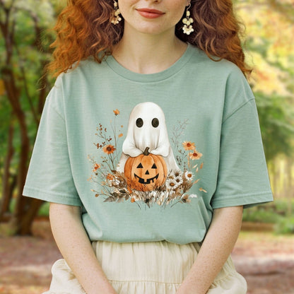 Boho ghost holding a jack o'lantern, surrounded by autumn florals, on a relaxed-fit sage green cotton t-shirt.